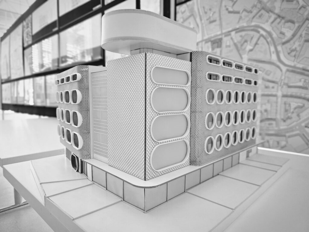 Architekturmodell eines modernen, mehrstöckigen Gebäudes mit abgerundeten, rechteckigen Fenstern, entworfen in Archicad, dargestellt auf einem Tisch mit einem Stadtplan im Hintergrund - zur Veranschaulichung der Transformation Kaufhaus für den Lebensraum von morgen.
